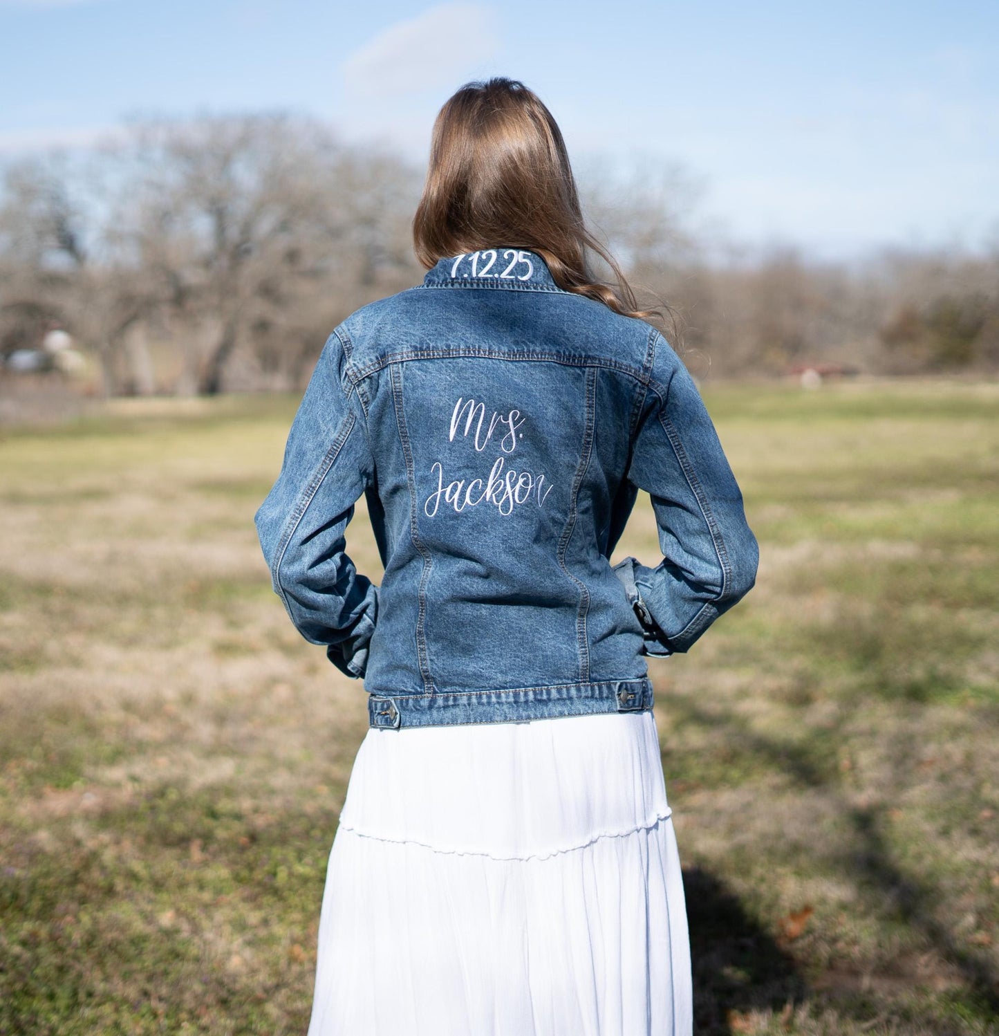 a woman standing in a field wearing a jean jacket