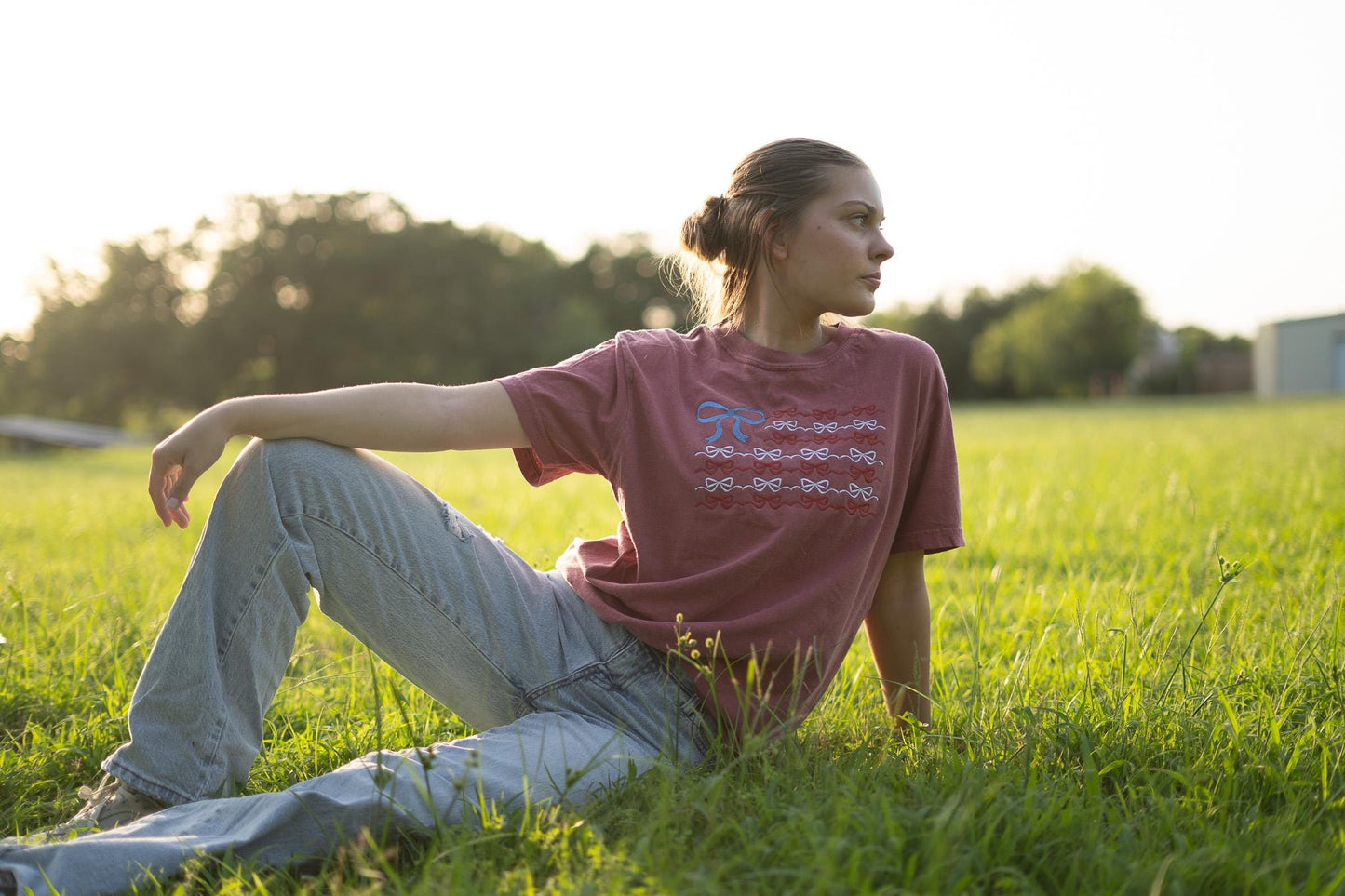 a woman sitting in the grass with her hand on her hip