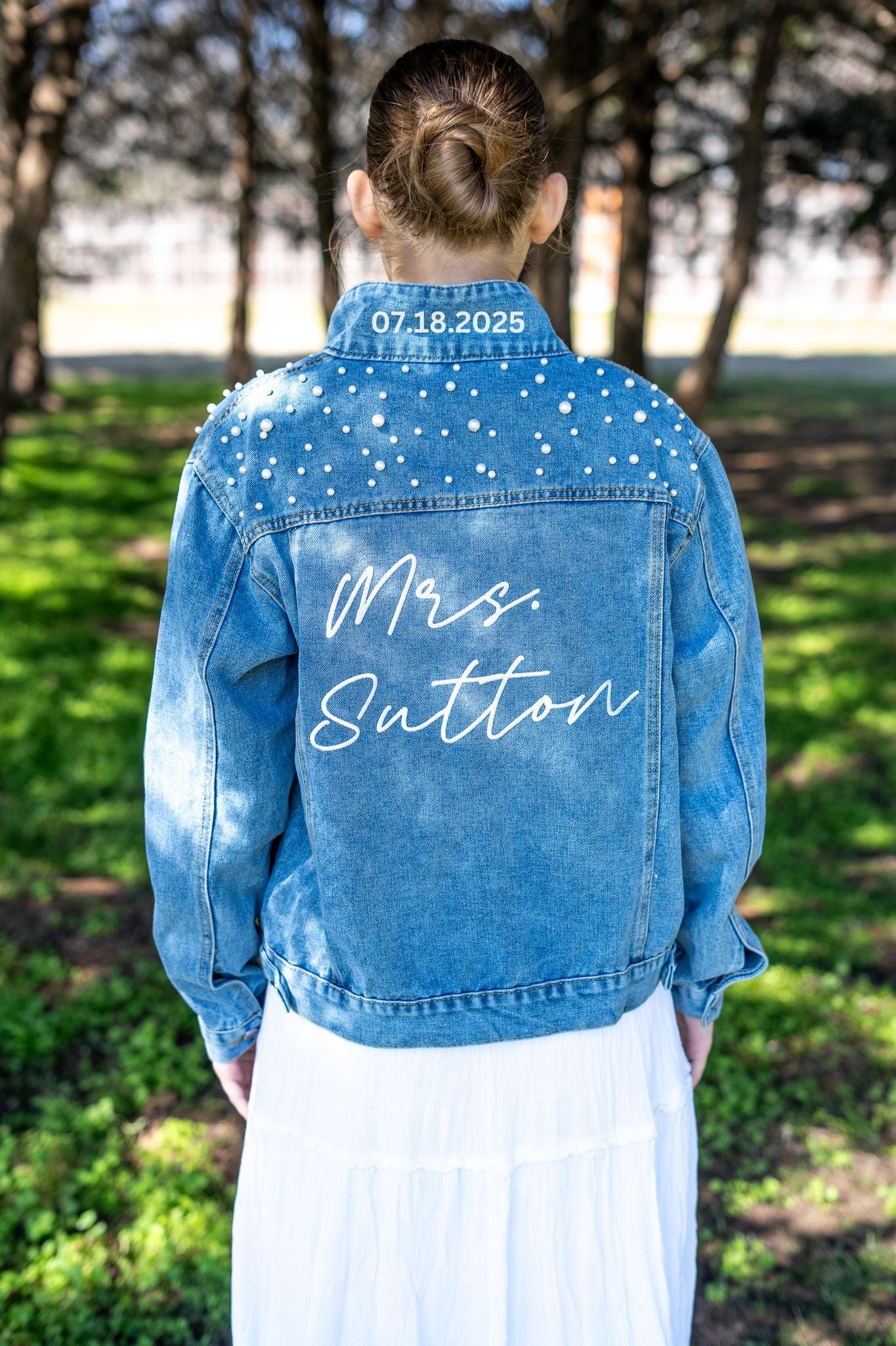 a woman wearing a jean jacket that says mrs button