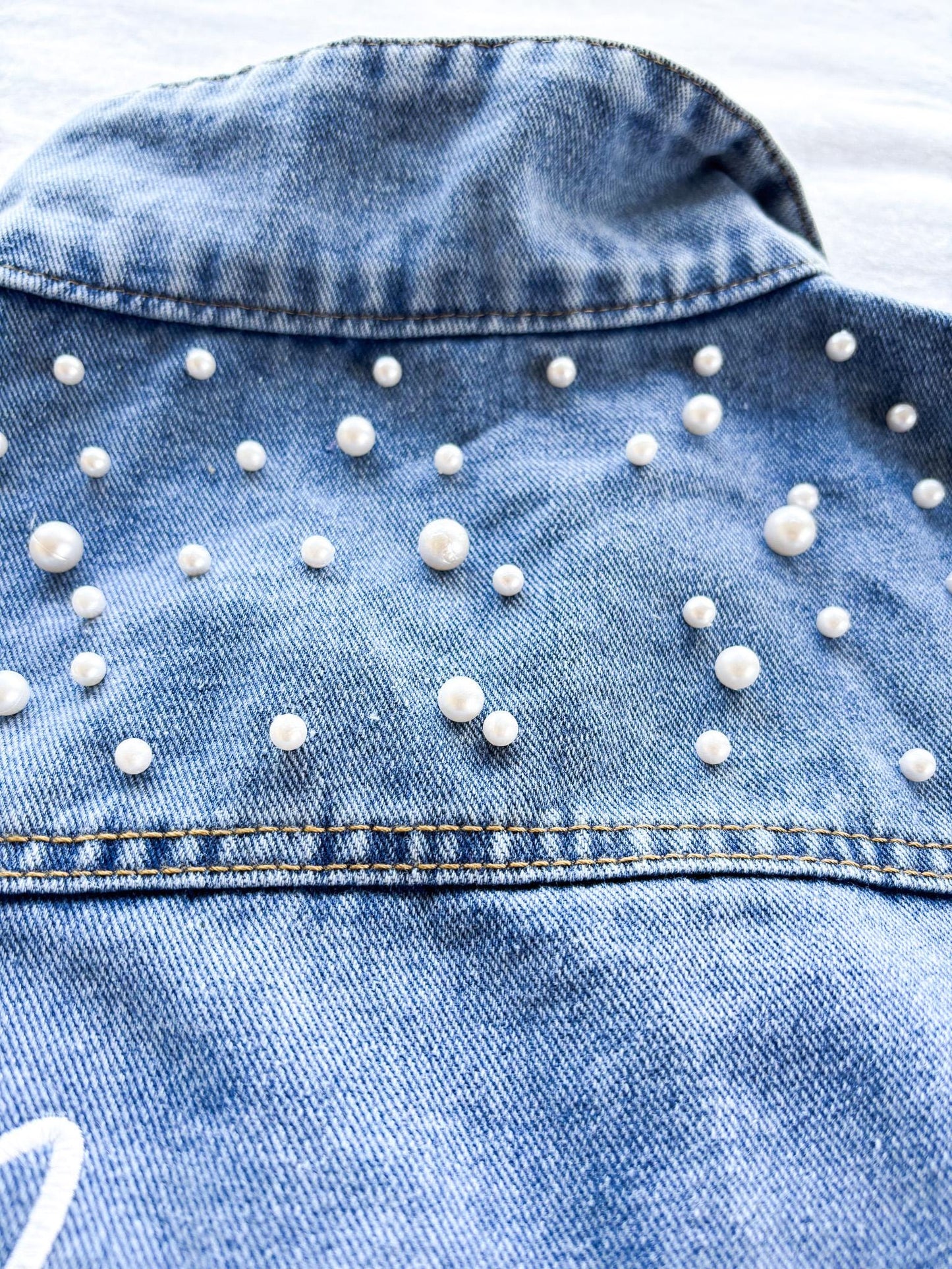 a denim jacket with white pearls on it
