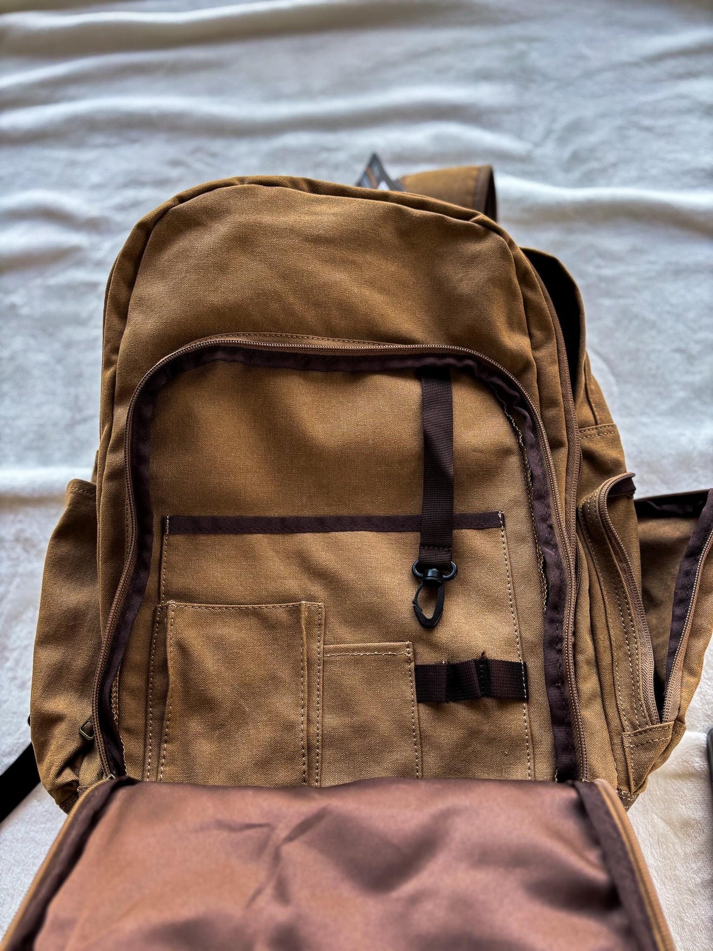 a brown backpack sitting on top of a bed