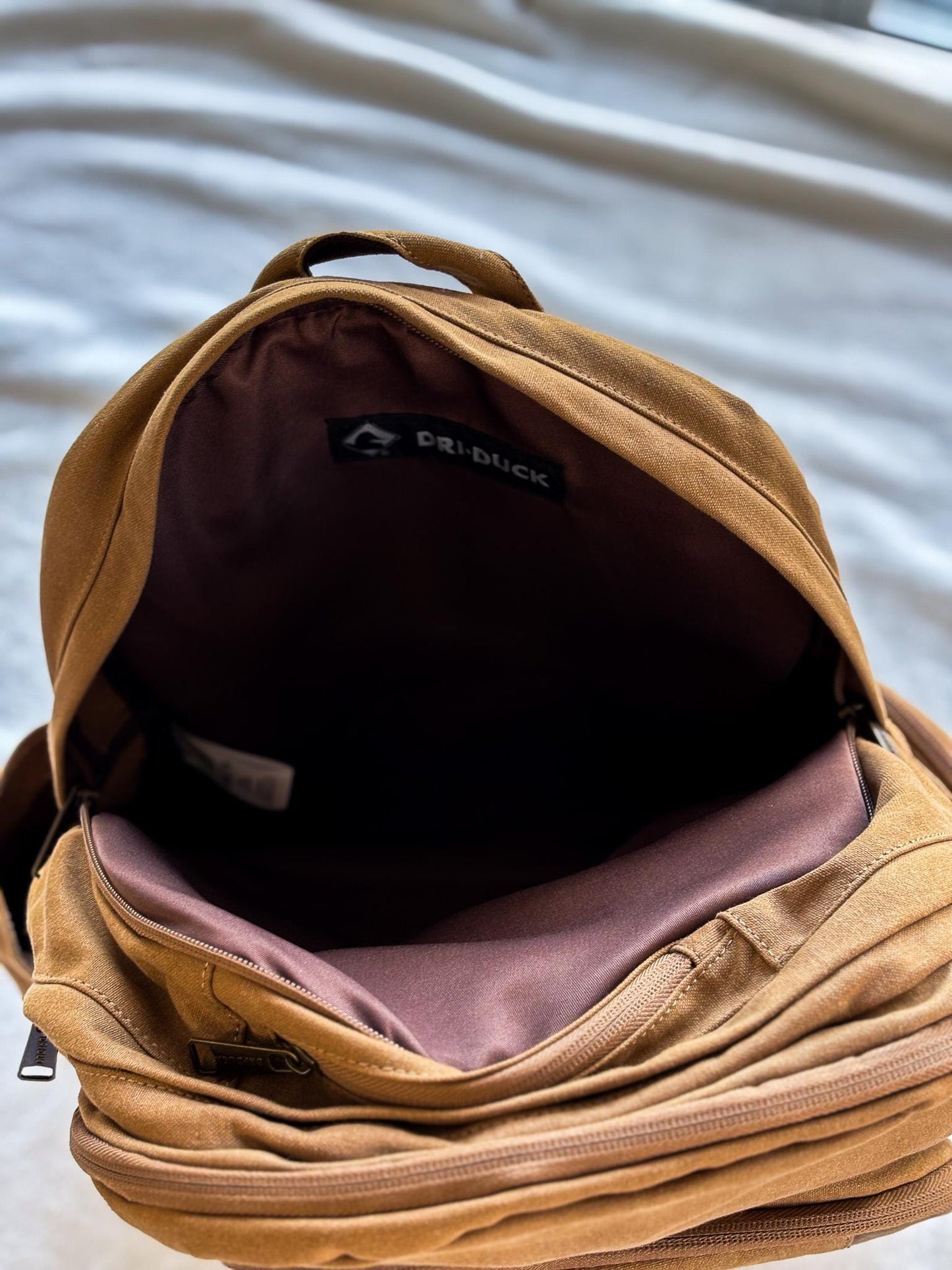 a brown backpack sitting on top of a bed