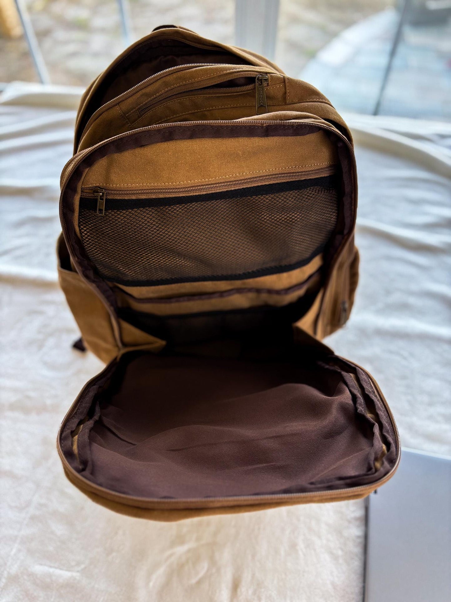 a brown backpack sitting on top of a bed