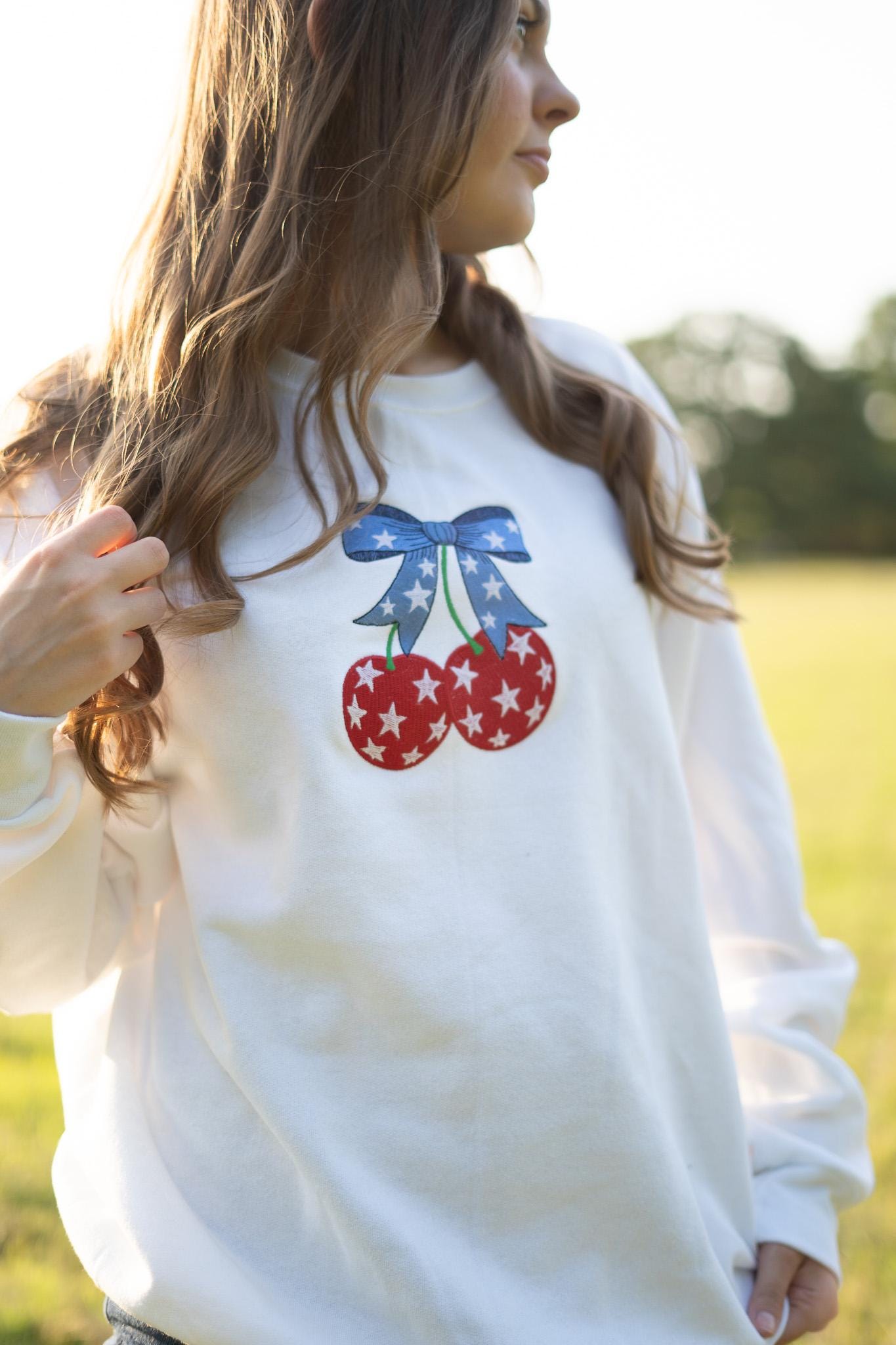 a woman wearing a white sweatshirt with cherries on it